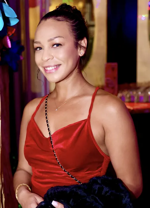 A woman in a red dress smiling at an evening celebration