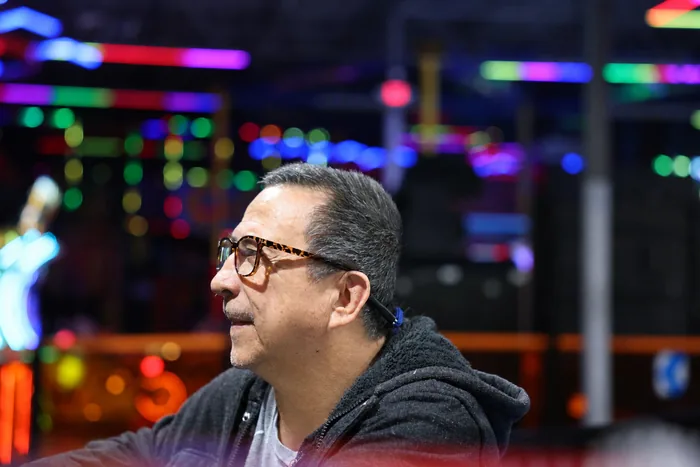 A man in glasses among the neon lights of an arcade
