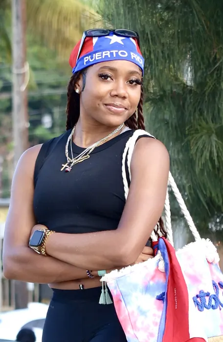 A woman in a black top and patterned head wrap outdoors