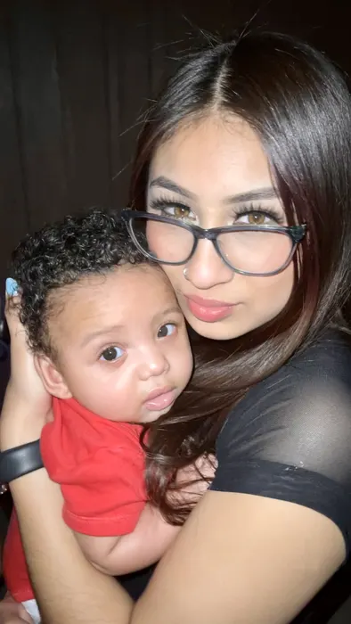 A woman holding a wide-eyed baby close to the camera
