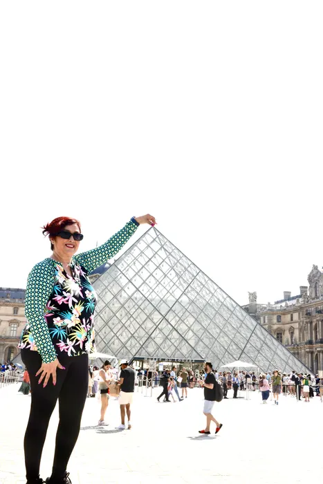 A traveler posing beside the glass pyramid at the Louvre