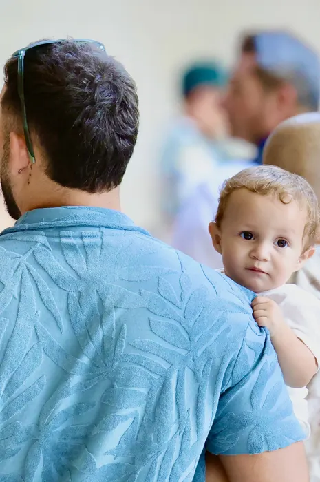 A man carrying a young child looking over his shoulder